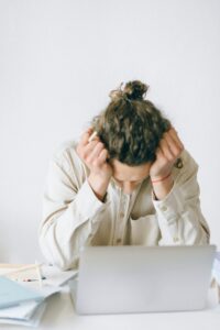 Overwhelmed person leaning over a laptop